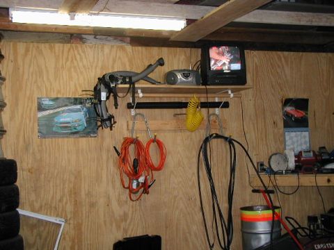 1994 Ford Probe - A cluttered garage scene displays various tools, a television, and automotive-themed calendars on a plywood wall.