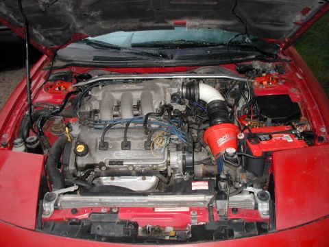 1994 Ford Probe - Engine bay of a 1994 Ford Probe, showing the engine, battery, and aftermarket modifications.