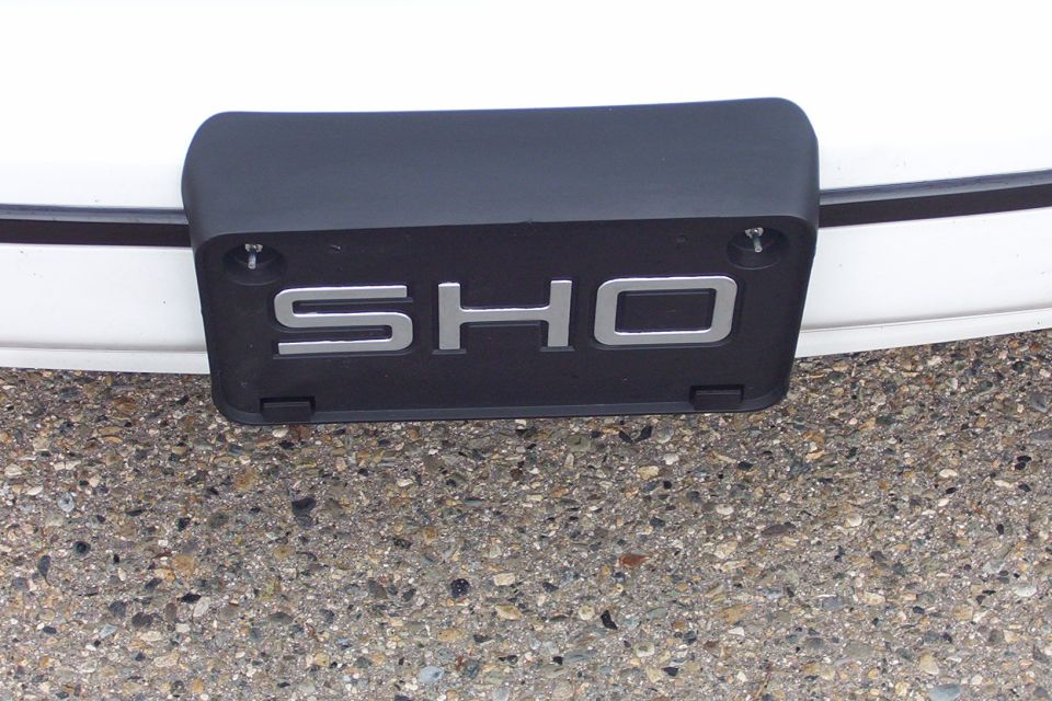 Close-up of a black car part with silver 'SHO' lettering