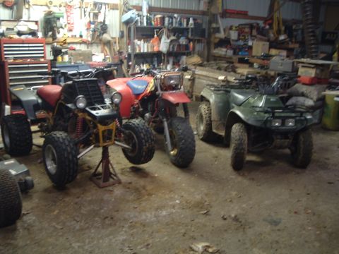 1995 Mercury Grand Marquis - Several all-terrain vehicles are stored inside a cluttered garage with tools and supplies visible.