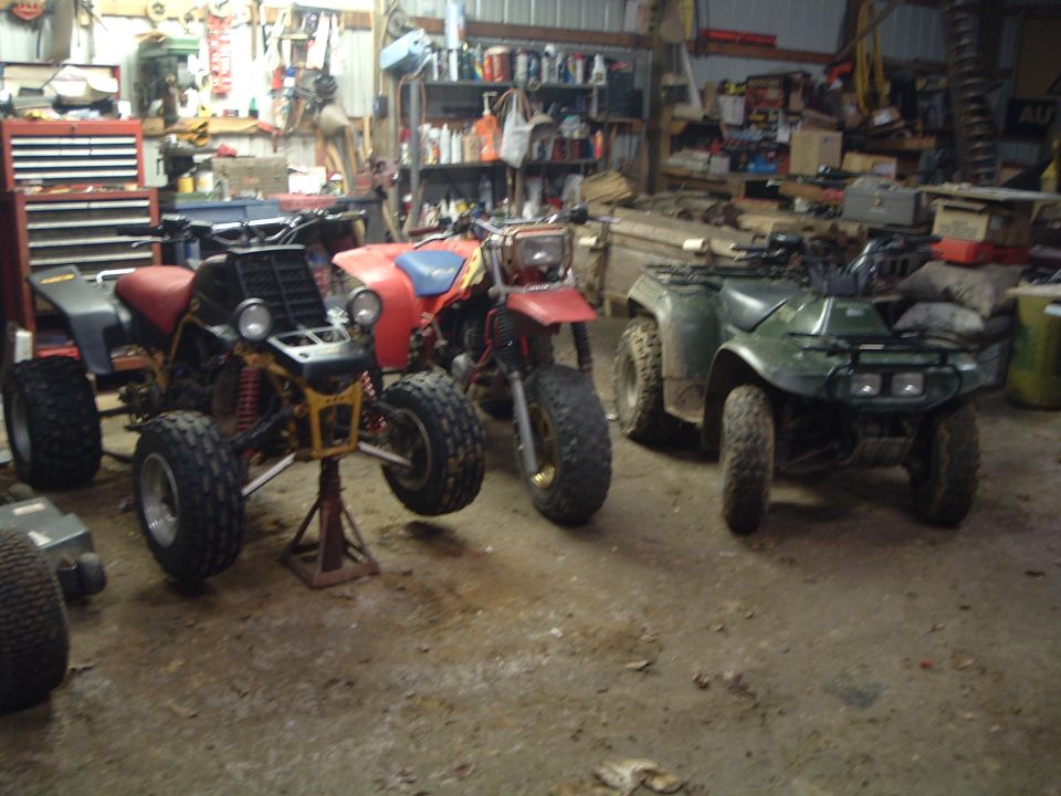three ATVs parked in a garage, one on a stand