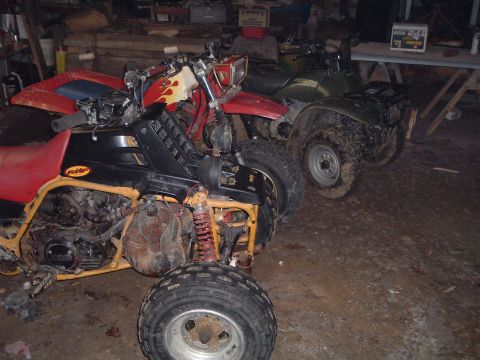 1995 Mercury Grand Marquis - Multiple ATVs are parked in a cluttered indoor space with a dirt floor.