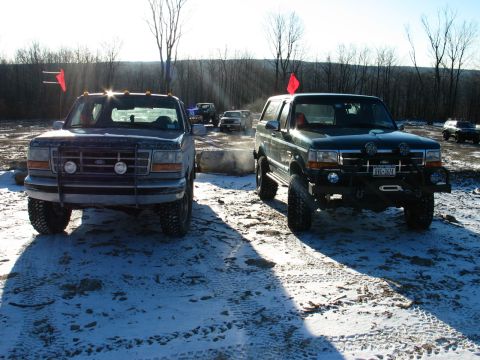 1995 Ford Bronco - Two 1995 Ford Broncos are parked in a snowy outdoor area, with trees in the background.