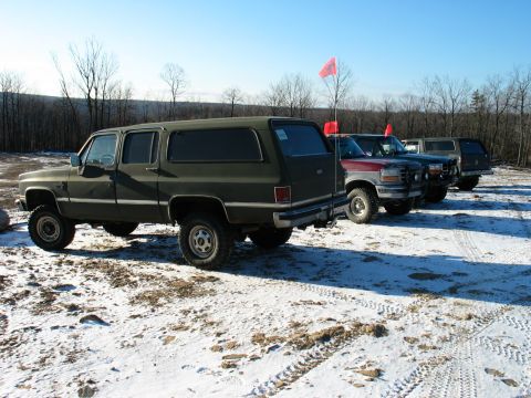 1995 Ford Bronco - Several SUVs are parked in a snowy field under a clear blue sky.