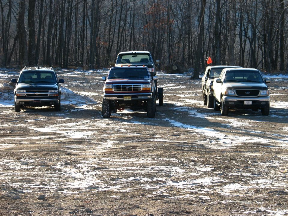 1995 Ford Bronco parked in front with three other trucks behind it