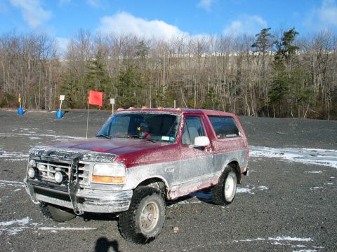 1995 Ford Bronco - This 1995 Ford Bronco, seen in a gravelly outdoor area, features a two-tone paint scheme and a prominent front grille guard.