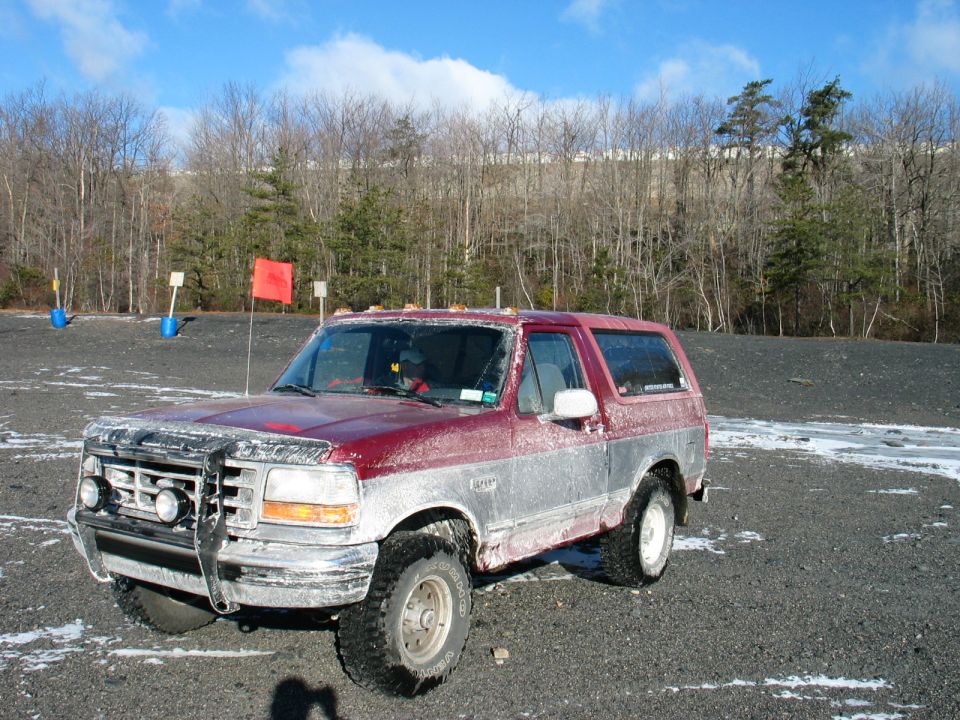 Red and silver 1995 Ford Bronco with aftermarket grille guard and roof lights