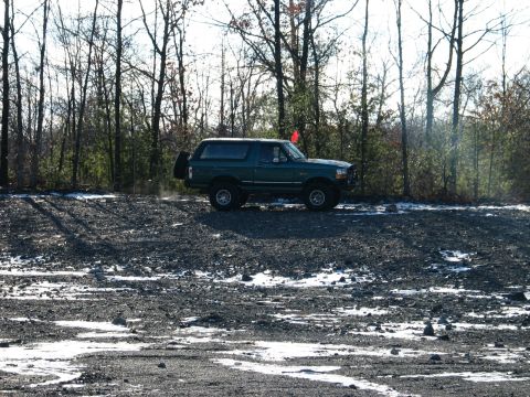 1995 Ford Bronco - 1995 Ford Bronco parked on gravel with a red flag on the antenna.