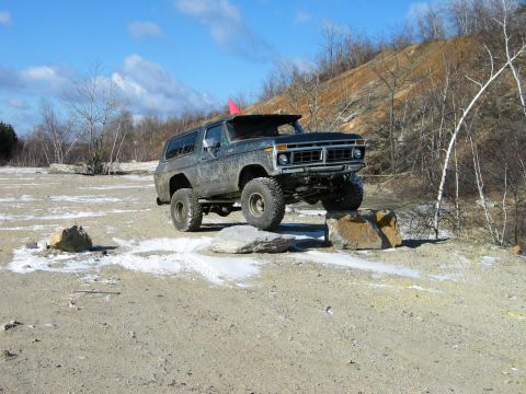 1995 Ford Bronco - This lifted Ford Bronco is navigating a rocky off-road course under a bright blue sky.