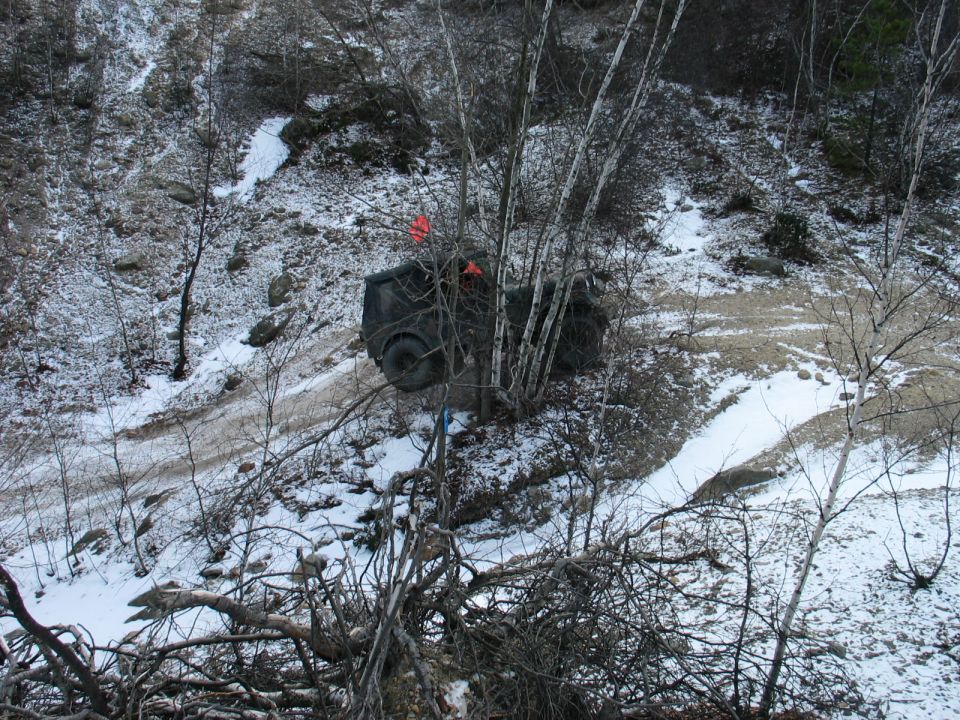 Dark SUV stuck in snow and mud on a wooded hillside