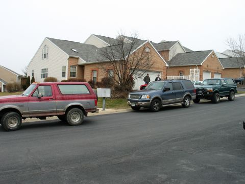 1995 Ford Bronco - Three SUVs parked on a residential street, including two Ford Broncos and a Ford Expedition.