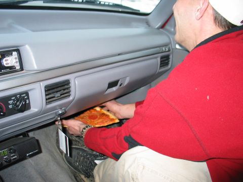 1995 Ford Bronco - A slice of pepperoni pizza is being placed into the glove compartment of a vehicle.