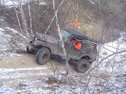1979 Ford Bronco - Off-road vehicle navigating a difficult trail and getting stuck amongst trees.