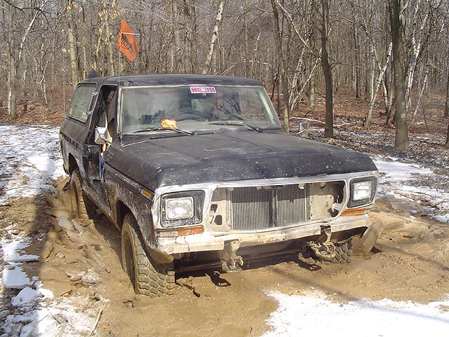 1979 Ford Bronco stuck in mud with an orange flag on a pole behind it