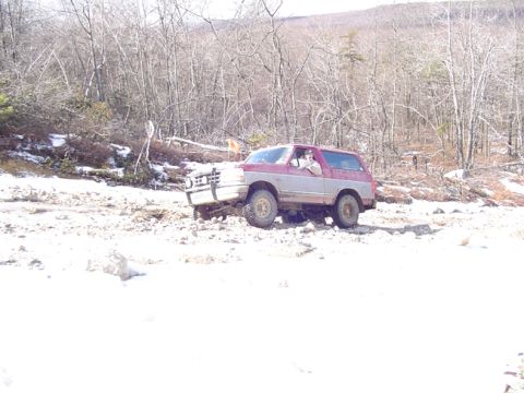 1979 Ford Bronco - This SUV is navigating a challenging, snow-covered terrain with sparse vegetation.