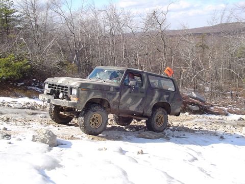 1979 Ford Bronco - Ford Bronco navigates a snowy, wooded terrain with an orange flag on its antenna.