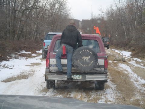 1979 Ford Bronco - Red Ford Bronco with spare tire on back, license plate CRT-1991, on a snowy dirt road with other vehicles.