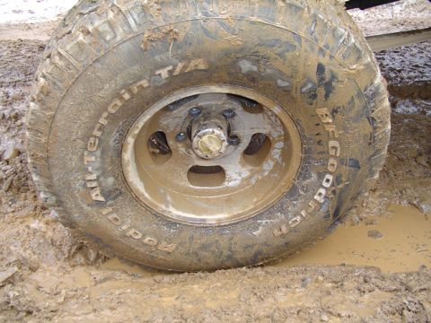 1979 Ford Bronco - Muddy off-road tire and wheel stuck in mud.