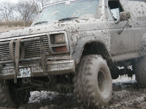 1985 Ford Bronco - This SUV is heavily covered in mud, obscuring many details but its body style suggests an older model.