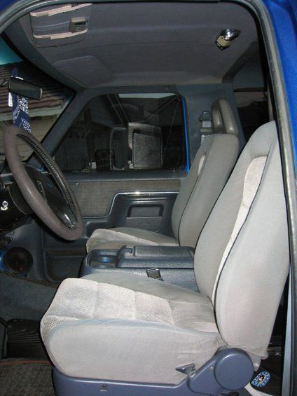 1989 Ford Bronco - The interior of a blue SUV shows the driver's side and passenger seats, center console, and dashboard.