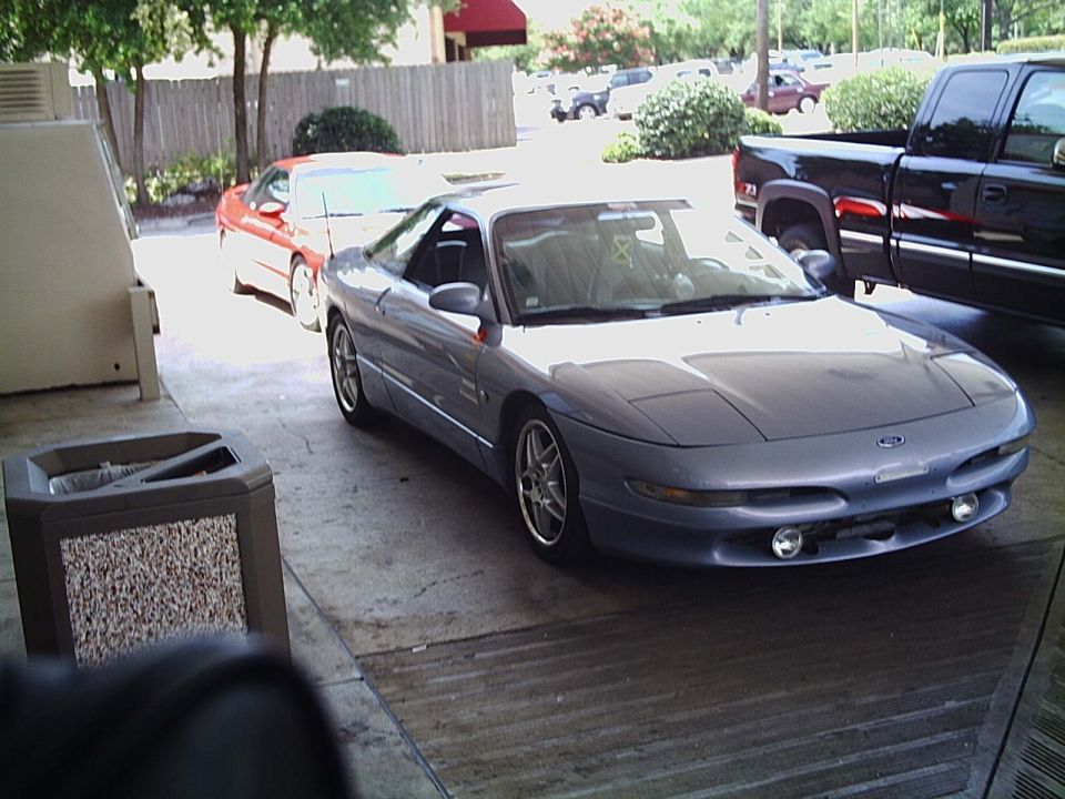 Silver Ford Probe coupe parked outside a building with an orange car and pickup nearby