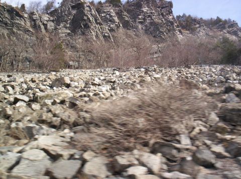 1995 Ford Bronco - A rocky landscape with cliffs and sparse vegetation, a Supermotors logo in the lower right corner.