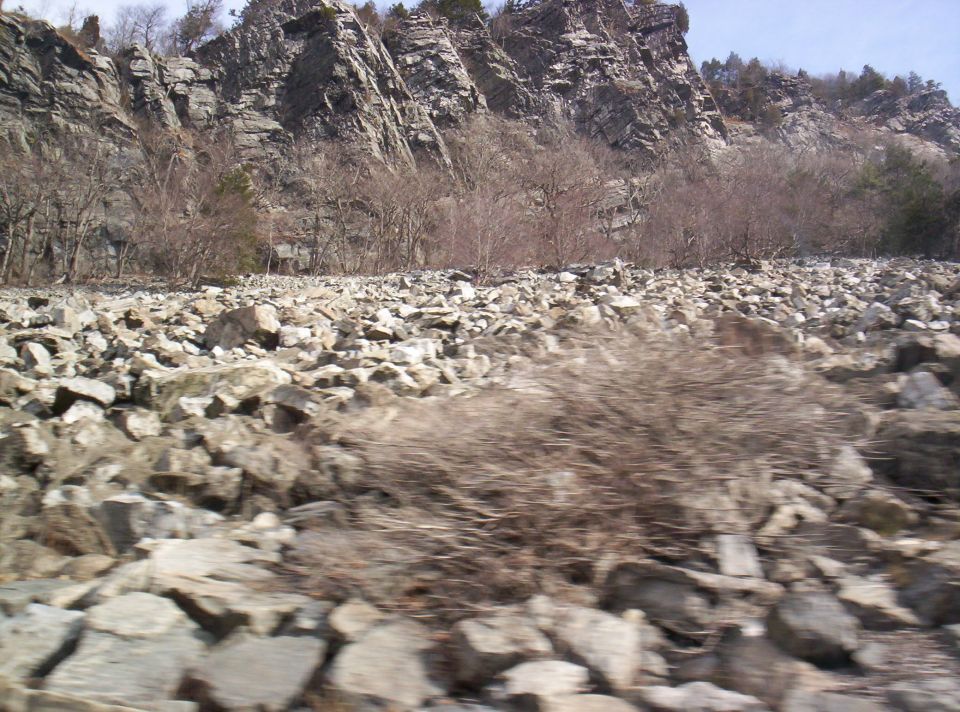 Rocky terrain with cliffs and bare trees, Supermotors logo visible
