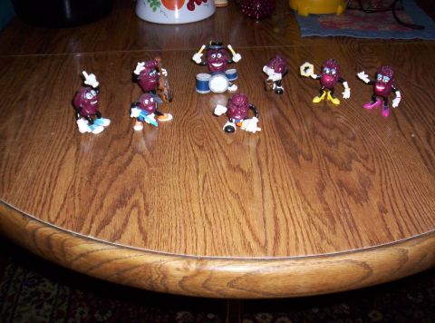 1971 Ford Mustang - A collection of The California Raisins toys are arranged on a wooden table surface.