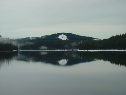 1986 Ford Bronco - A winter landscape a calm lake reflecting the surrounding snow-dusted hills and dense evergreen forests.