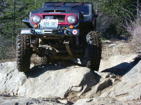 1990 Ford Bronco - This off-road vehicle navigates a rocky trail, its powerful suspension and aggressive tires.