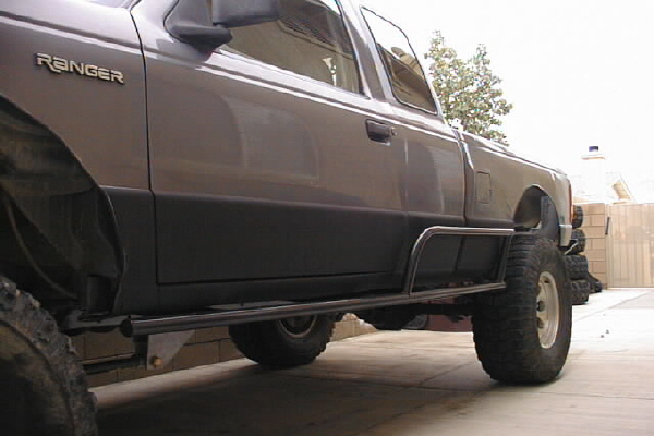Dark gray Ford Ranger extended cab pickup with tube rock sliders and off-road tires, low side view
