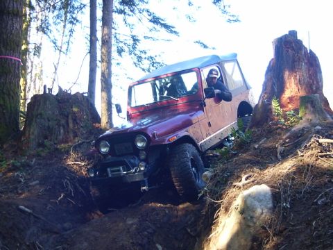 1990 Ford Bronco - Jeep CJ-7 tackling a challenging off-road course with steep inclines and obstacles.