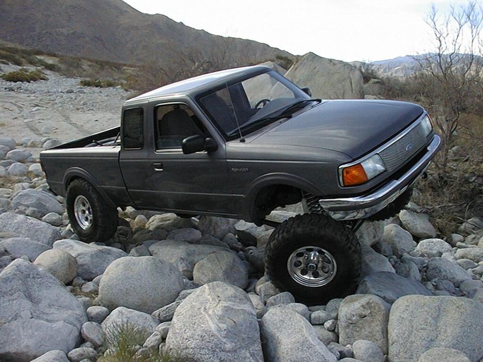 Gray Ford Ranger extended cab lifted and climbing a boulder field in the desert