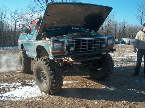 1995 Ford Bronco - Modified Ford Bronco with hood up, parked on dirt with snow patches. Engine visible.