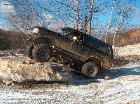 1995 Ford Bronco - A heavily modified SUV navigates a challenging off-road course, demonstrating its capabilities on rough terrain.