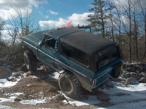 1995 Ford Bronco - Teal Ford Bronco navigating rough terrain with snow on the ground.