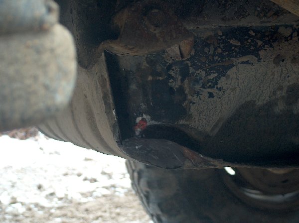 Undercarriage of a vehicle with rust and dirt visible on metal components near a tire
