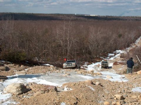 1995 Ford Bronco - Off-roading scene with two SUVs on a difficult trail in winter conditions.