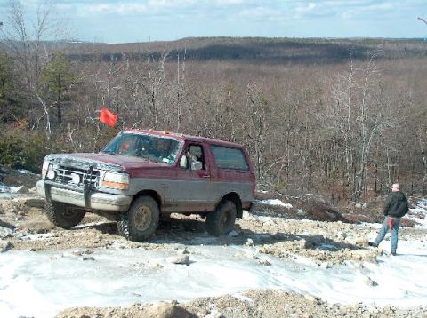 1995 Ford Bronco - A Ford Bronco navigates a challenging off-road course in a wooded area during winter.
