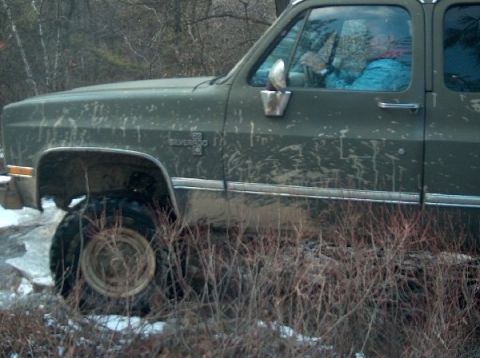 1995 Ford Bronco - A muddy Chevrolet Silverado navigates through brush and snow.