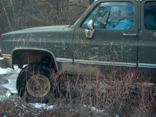 Mud-splattered green Chevrolet Silverado driving off-road