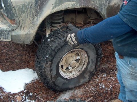 1995 Ford Bronco - Flat tire on a muddy off-road vehicle, with snow on the ground.