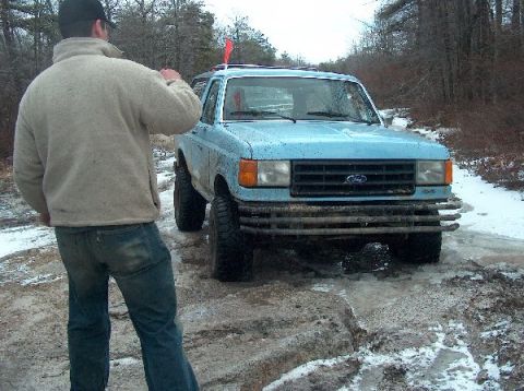 1995 Ford Bronco - Ford Bronco stuck in mud and snow, likely off-roading. The vehicle appears to be from the early 1990s.
