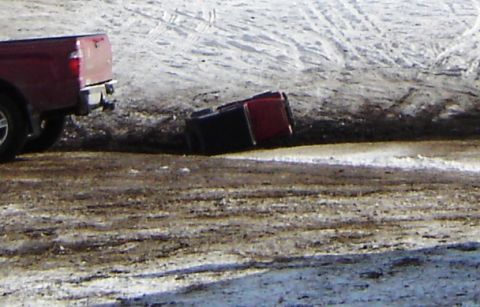 1978 Chevrolet C/K Pickup - A red pickup truck has overturned in a snowy ditch, with another red pickup truck visible nearby.