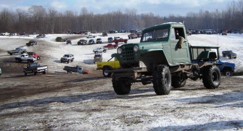1978 Chevrolet C/K Pickup - A heavily modified green truck sits in a muddy and snowy area, surrounded by many other vehicles.