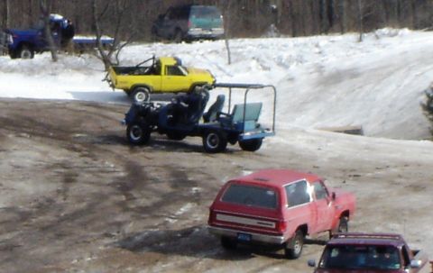 1978 Chevrolet C/K Pickup - Several vehicles are parked in a snowy outdoor area, including a red SUV and a yellow pickup truck.
