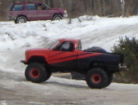 1978 Chevrolet C/K Pickup - Lifted 1978 Chevrolet C/K Pickup with custom paint and large tires navigates a snowy road.