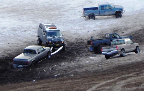 1978 Chevrolet C/K Pickup - Several trucks and a van are stuck in a muddy, snowy terrain.