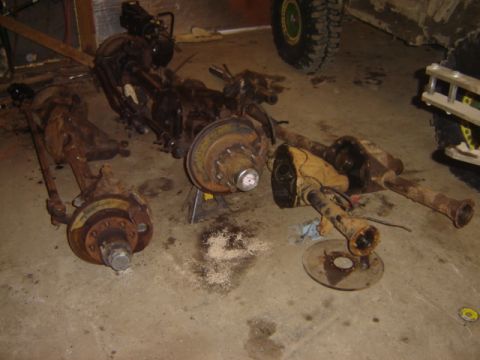 1992 Ford Bronco - Several vehicle axle assemblies and suspension components are disassembled and resting on the floor.