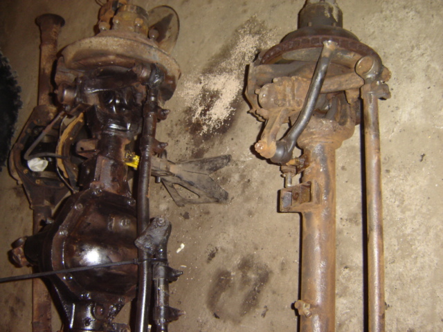 Two rusty Dana 60 axles, one with brake drum, on concrete floor